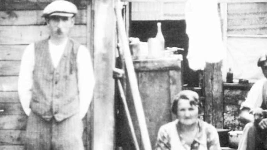 Bild schwarz-weiß einer Familie vor ihrem Elendsquartier, um 1930
