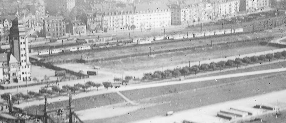 schwarz-weißes Luftbild von 1927 mit der Friedrichsbrücke (heute Kurpfalzbrücke). Oben rechts die Alte Feuerwache und dahinter das Neckarufer mit Beginn des Teilstücks „Weißer Sand“