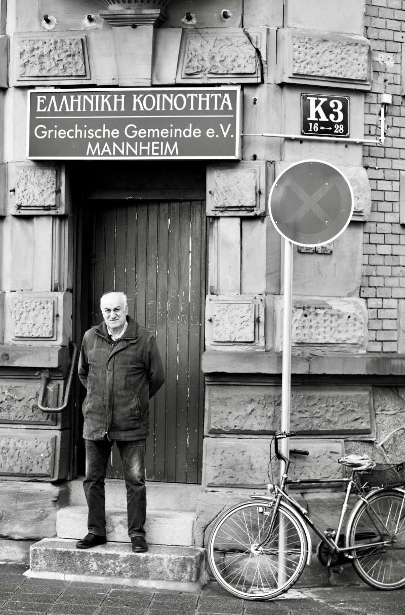 schwarz-weiß Foto von einem Mann, der vor dem Verein Griechische Gemeinde Mannheim steht