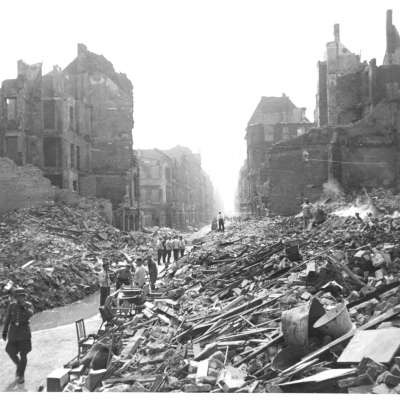 Zerstörung Mannheims im Zweiten Weltkrieg in den Quadraten T3 und T4. Menschen laufen zwischen den Trümmern.