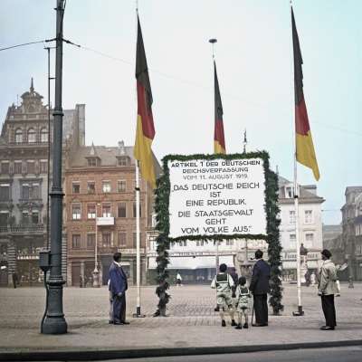 Ein coloriertes Foto aus der Weimarer Republik. Auf einem großen Transparent am Marktplatz steht geschrieben: "Artikel 1 der deutschen Reichsverfassung vom 11. August 1919. "Das deutsche Reich ist eine Republik. Die Staatsgewalt geht vom Volke aus.""