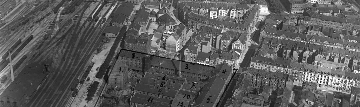 Links sind eine Vielzahl von Schienen zu sehen, daneben das Werksgelände der Firma Mohr & Federhaff aus der Luft fotografiert mit handschriftlich nummerierten Hallen