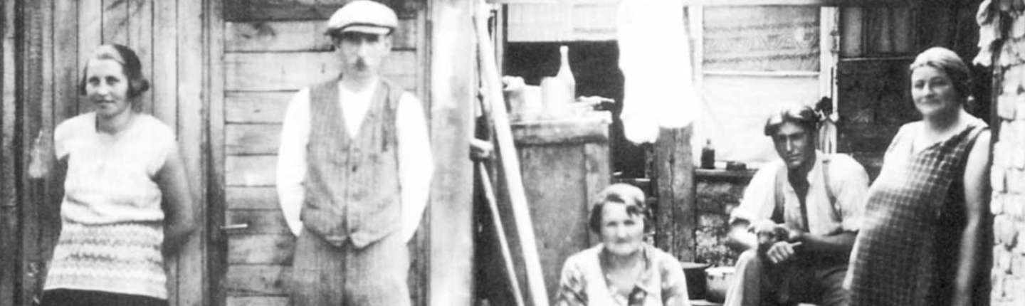 Bild schwarz-weiß einer Familie vor ihrem Elendsquartier, um 1930
