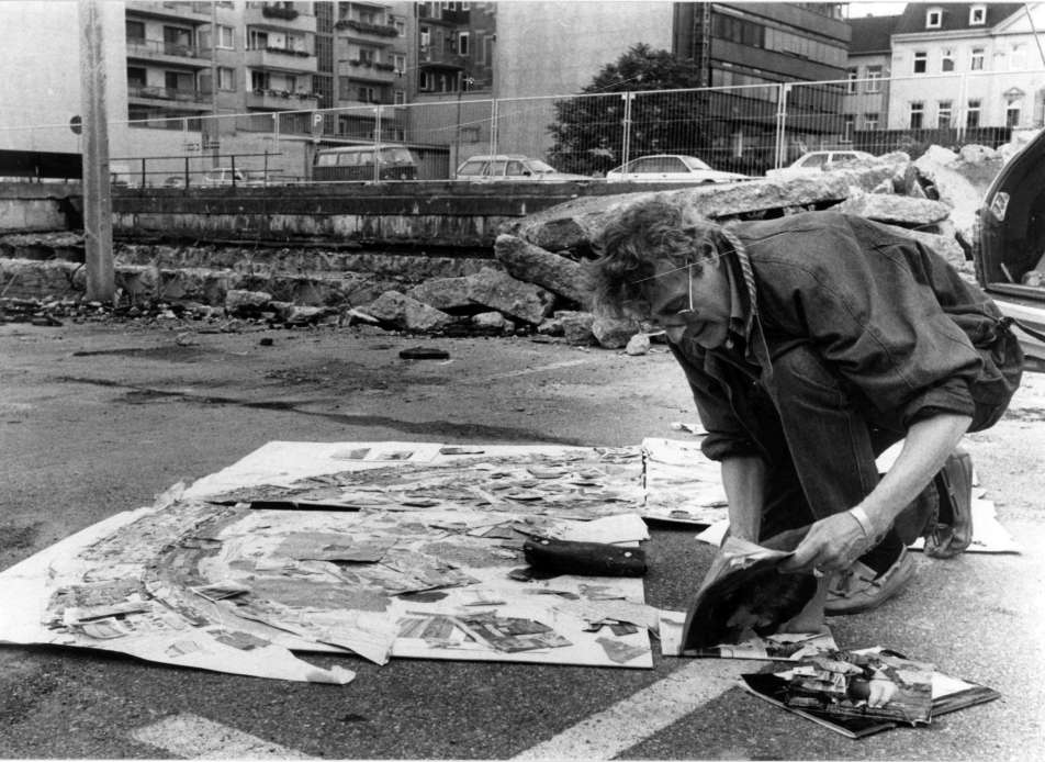 schwarz-weiß Foto des Künstlers Norbert Nüssle kniend auf dem Boden bei der Arbeit